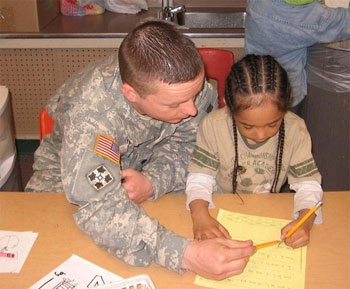 A soldier works with a kindergarten student at Chester Valley Elementary School in Anchorage, Alaska.